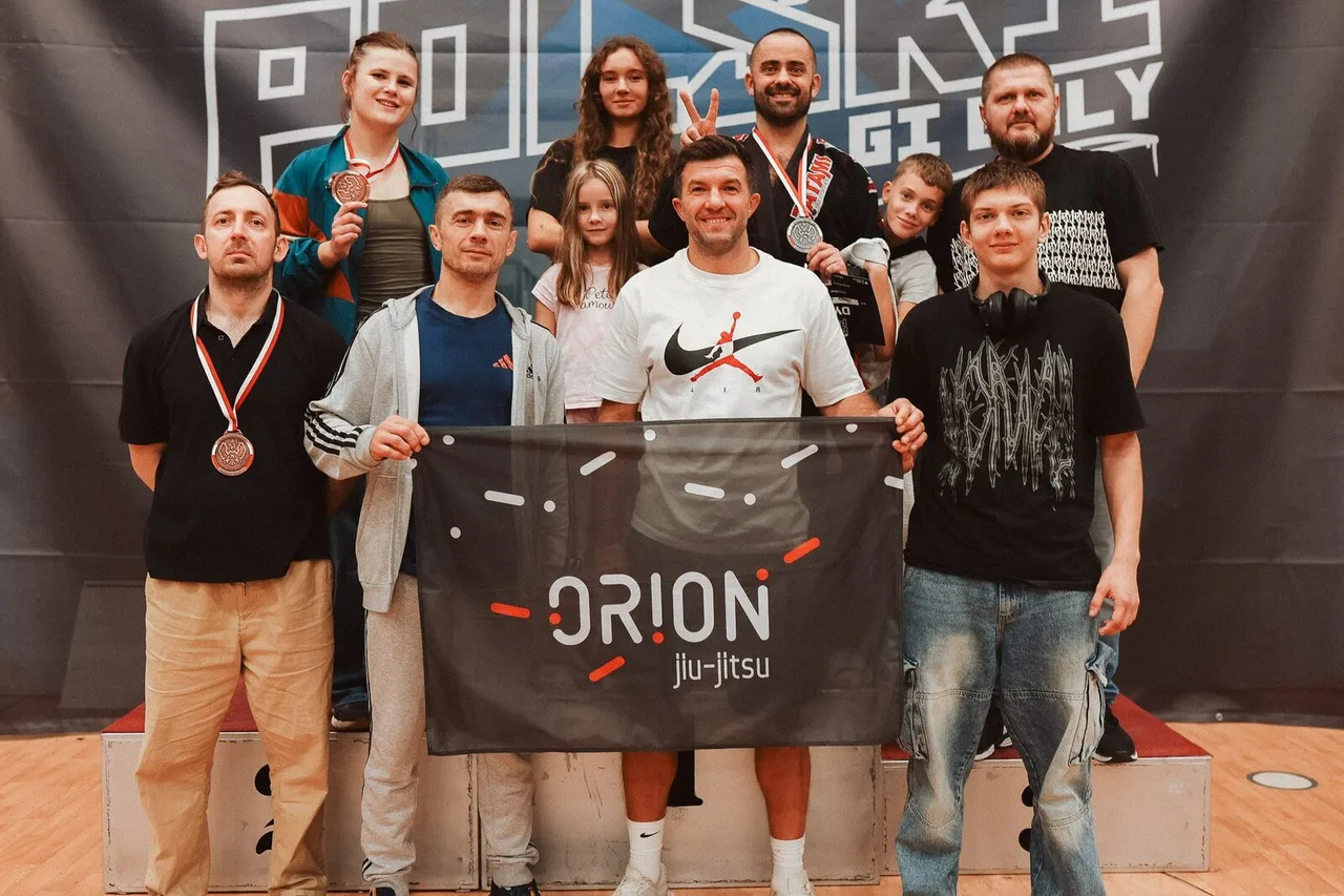 Команда Orion BJJ Wrocław с баннером клуба на подиуме